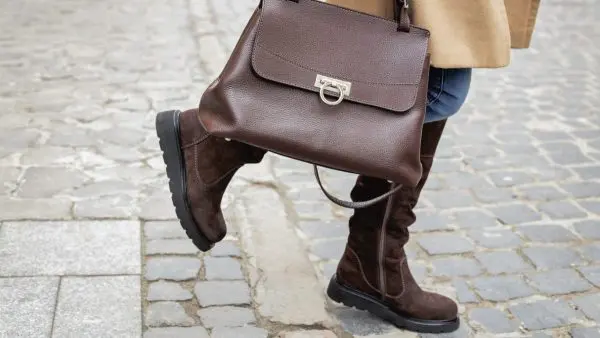 γυναίκα φοράει καφέ σουέτ μπότες και καφέ τσάντα