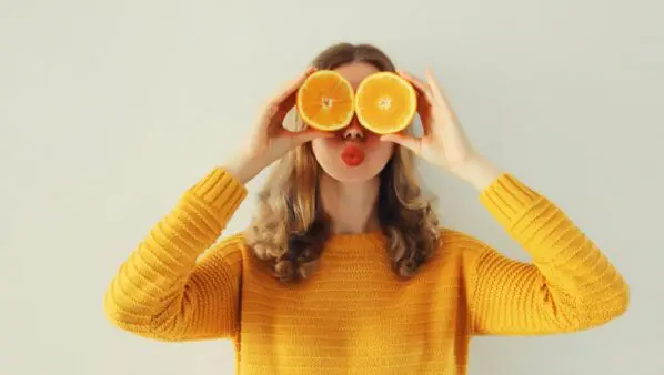 κορίτσι κρατάει πορτοκάλια μπροστά στα μάτια του
