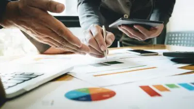 Χαρτιά σε γραφείο και δύο αντρικά χέρια που κρατούν σημειώσεις