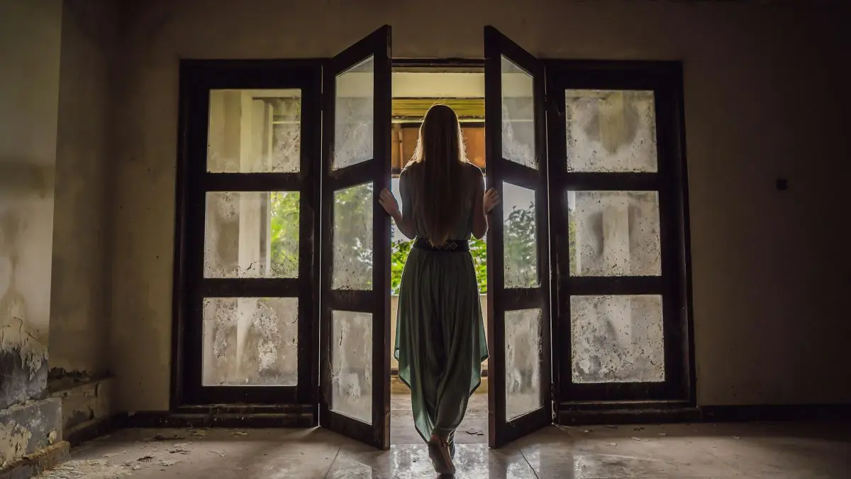 μια κοπέλα ανοίγει μια παλιά πόρτα