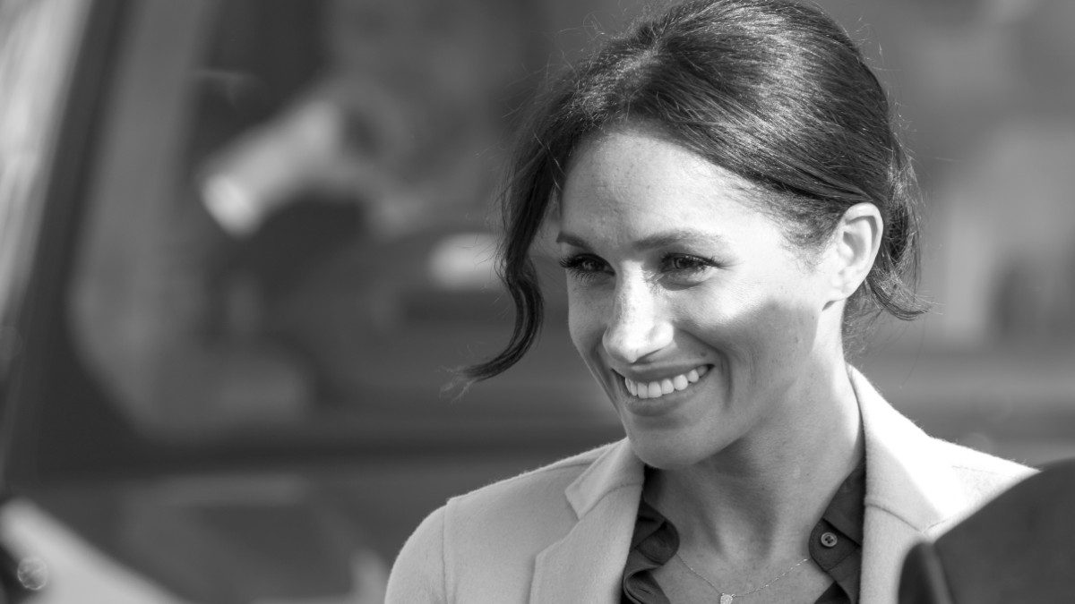 Η Μέγκαν Μαρκλ με μαύρο πουκάμισο και λευκό παλτό