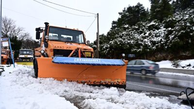 Χιονισμένος δρόμος και ένα πορτοκαλί εκχιονιστικό