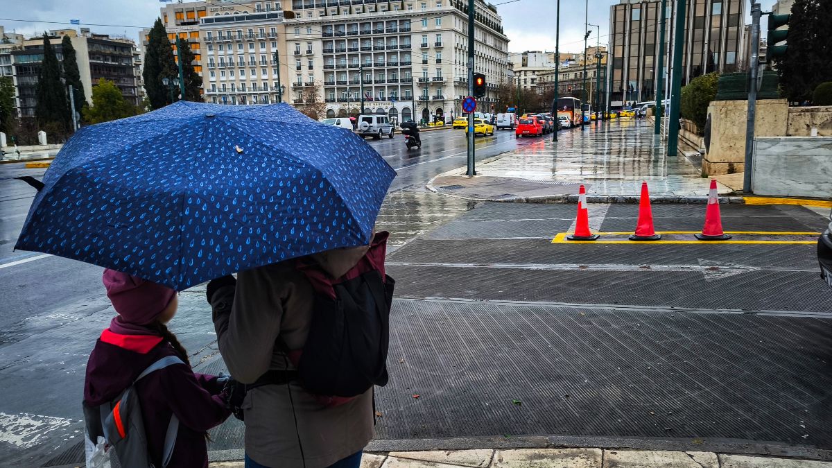 Μπαμπάς και γιος με ομπρέλα σε βροχερό τοπίο της Αθήνας