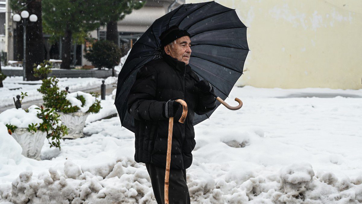 Ένας παππούς με ομπρέλα σε χιονισμένο τοπίο