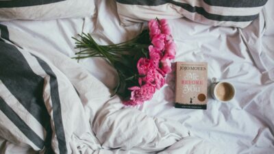 Ένα κρεβάτι με ένα μπουκέτο λουλούδια κι ένα βιβλίο επάνω
