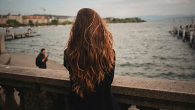 Μια γυναίκα με μπόλικα μαλλιά κοιτάει την παραλία