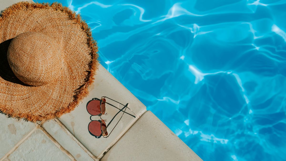 Ένα ψάθινο καπέλο και γυαλιά ηλίου σε μια πισίνα
