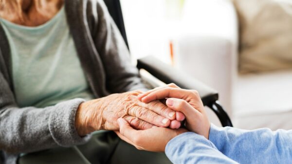 Μια νοσοκόμα κρατά τα χέρια μιας γιαγιάς
