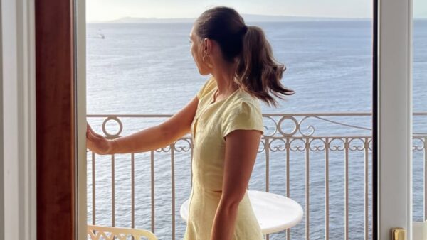 Κίτρινο φόρεμα φοράει κοπέλα σε μπαλκόνι