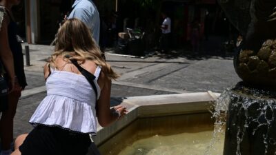 Μια κοπέλα βουτάει το χέρι της στο συντριβάνι του συντάγματος