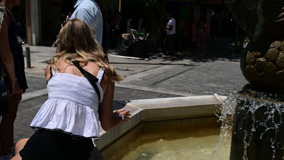 Μια κοπέλα βουτάει το χέρι της στο συντριβάνι του συντάγματος